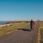 Das Foto zeigt einen Radfahrer auf dem Rheindamm im Kreis Wesel