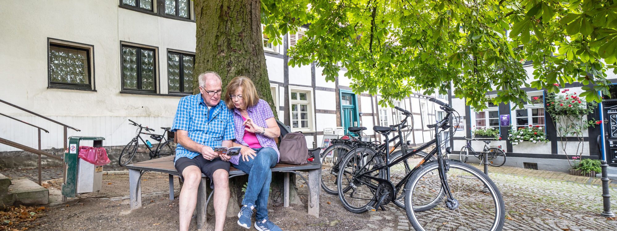 Das Foto zeigt zwei Radfahrende mit Tourenheft in der Altstadt von Unna bei der RevierRoute Handelswege