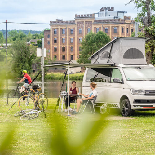 The photo shows cyclists camping with a Bulli on a campsite in Hattingen an der Ruhr
