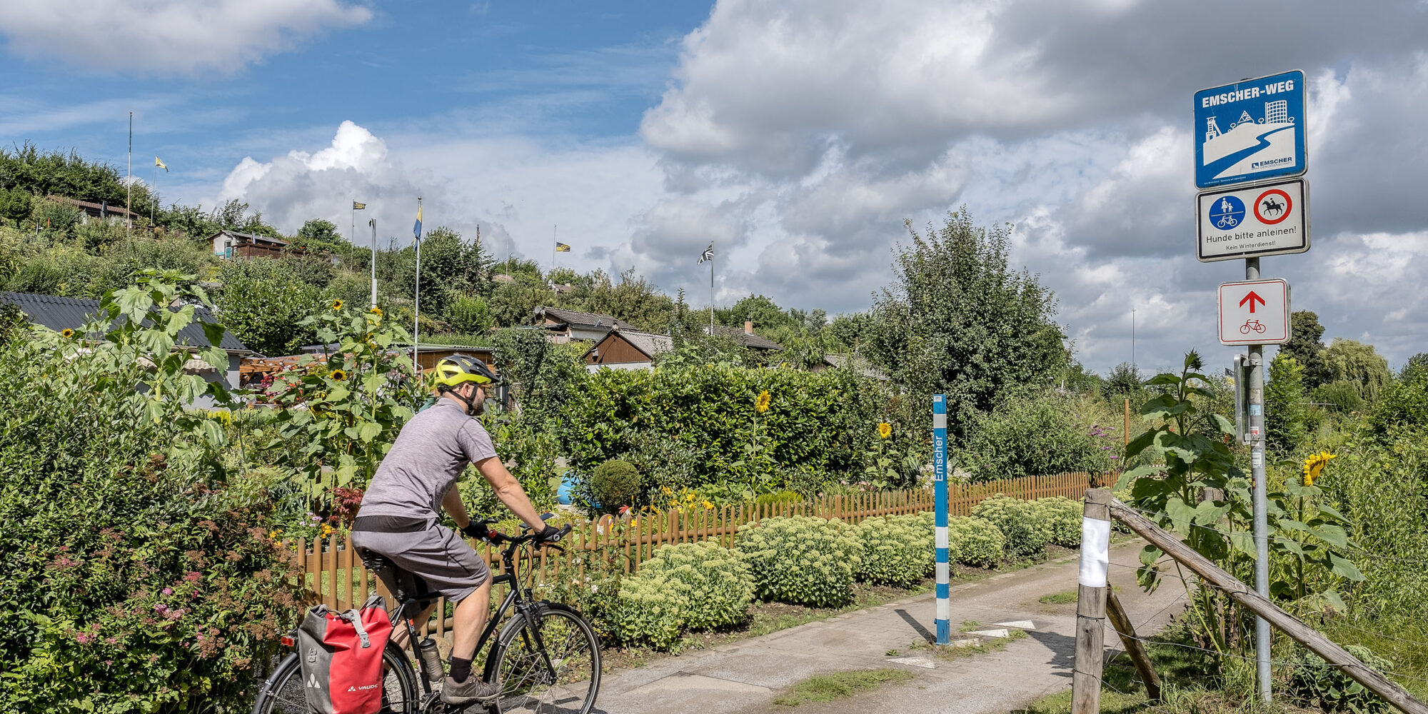 Das Foto zeigt einen Radfahrer auf dem Emscher Weg in einer Kleingartenanlage in Dortmund