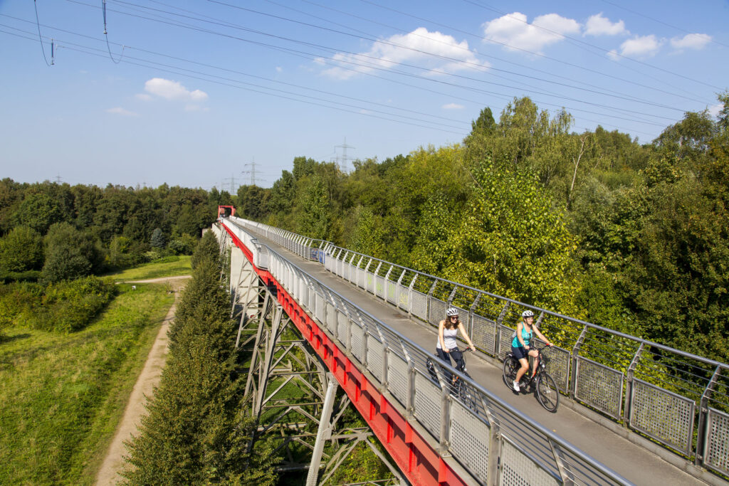 Das Foto zeigt zwei Radfahrerinnen auf der Erzbahnbrücke der Erzbahntrasse in Gelsenkirchen auf der RevierRoute Probierstück