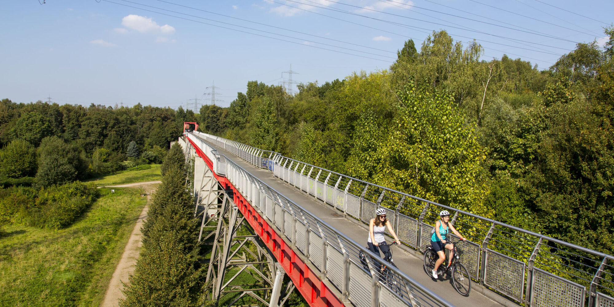 Das Foto zeigt zwei Radfahrerinnen auf der Erzbahnbrücke der Erzbahntrasse in Gelsenkirchen auf der RevierRoute Probierstück