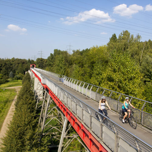 Das Foto zeigt zwei Radfahrerinnen auf der Erzbahnbrücke der Erzbahntrasse in Gelsenkirchen auf der RevierRoute Probierstück