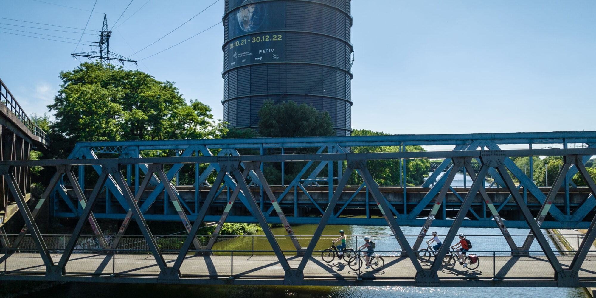 Das Foto zeigt Radfahrende auf dem Radweg entlang des Rhein-Herne-Kanals am Gasometer Oberhausen