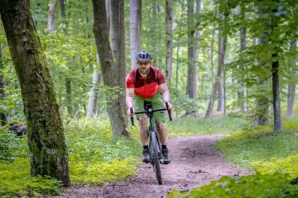 Das Foto zeigt einen Radfahrer auf einem Gravelbike in einem Wald in Duisburg