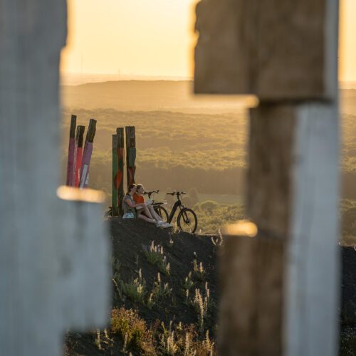 Das Foto zeigt zwei Radfahrerinnen beim Sonnenuntergang auf der Halde Haniel in Bottrop