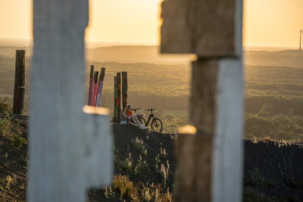 Das Foto zeigt zwei Radfahrerinnen beim Sonnenuntergang auf der Halde Haniel in Bottrop