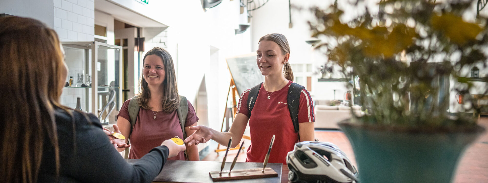 Das Foto zeigt zwei Radfahrerinnen beim Check in im Bett + Bike Hotel Alte Lohnhalle in Essen