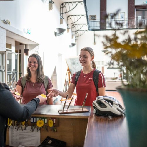 Das Foto zeigt zwei Radfahrerinnen beim Check in im Bett + Bike Hotel Alte Lohnhalle in Essen