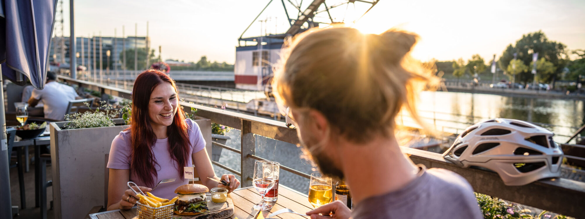 Das Foto zeigt zwei Radfahrende beim Essen im Innenhafen Duisburg