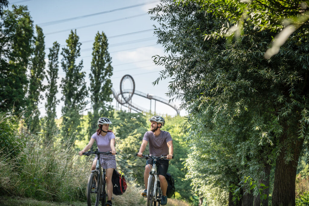 Das Foto zeigt Radfahrende auf der Heinrich-Hildebrand-Höhe mit dem Kunstwerk Tiger & Turtle in Duisburg