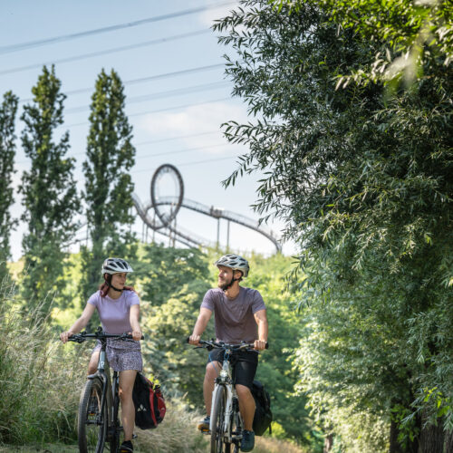 Das Foto zeigt Radfahrende auf der Heinrich-Hildebrand-Höhe mit dem Kunstwerk Tiger & Turtle in Duisburg