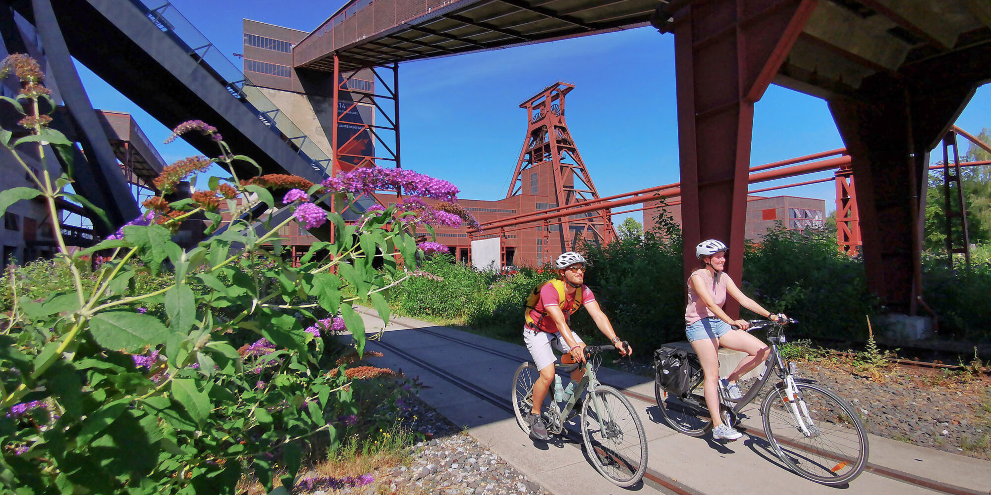 Das Foto zeigt zwei Radfahrende am UNESCO-Welterbe Zollverein in Essen auf der RevierRoute Grubenfahrt
