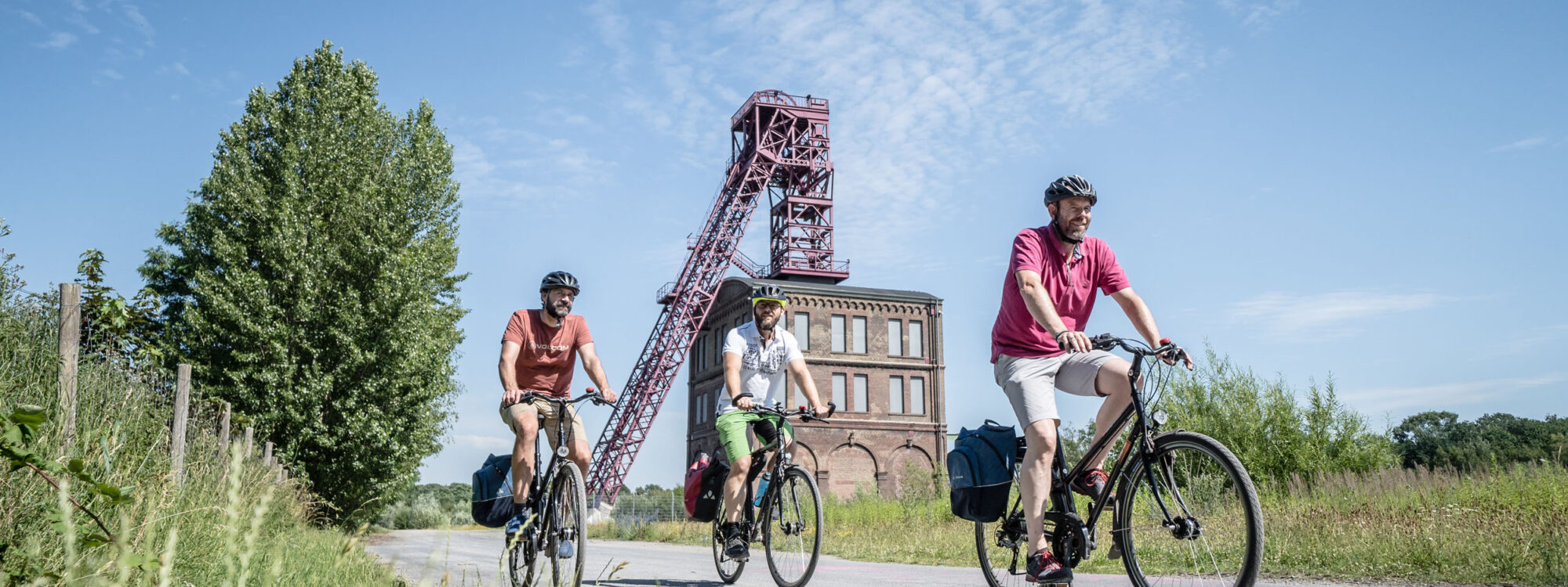 Das Foto zeigt drei Radfahrer beim Bahntrassenradeln auf der HOAG-Trasse in Oberhausen vor der Zeche Sterkrade bei der RevierRoute Stahlküche